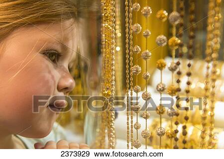 Stock Photo - Young girl looking at gold jewellery for sale in window of shop in the gold souk; Dubai, United Arab Emirates. Fotosearch