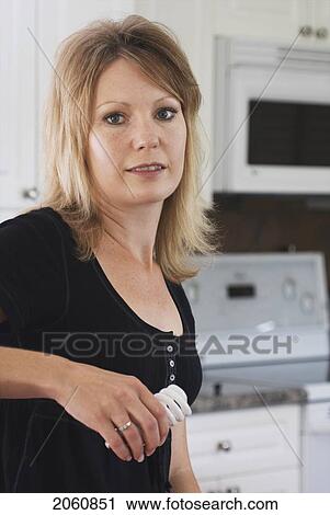 Stock Image - 40 Ish Woman Holding Compact Flourescent Light Bulb, Brandon, Canada. Fotosearch