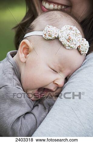 A baby girl yawns as she is held in her mother's arms; Edmonton, Alberta, Canada View Large Photo Image Stock Photo - A baby girl yawns as she is held in her mother's arms; Edmonton, Alberta, Canada. Fotosearch