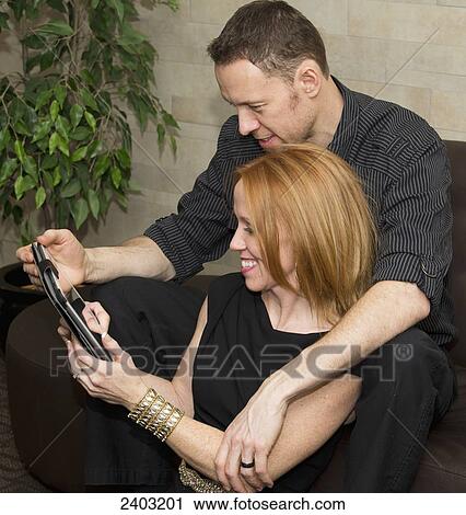 Stock Image - A couple looking at a tablet together, wife with a disability; Edmonton, Alberta, Canada. Fotosearch