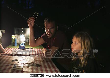 A father and daughter playing cards on a picnic table at night by the light of a lantern while camping; Peachland, British Columbia, Canada View Large Photo Image Stock Photograph - A father and daughter playing cards on a picnic table at night by the light of a lantern while camping; Peachland, British Columbia, Canada. Fotosearch