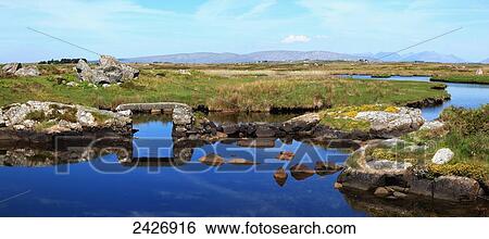 A landscape of grass with rock, tranquil water and mountains in the distance, near Casla; County Galway, Ireland View Large Photo Image Stock Photograph - A landscape of grass with rock, tranquil water and mountains in the distance, near Casla; County Galway, Ireland. Fotosearch