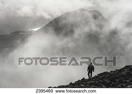 Stock Photo - A man walks out of the clouds from the summit of Maol Chean-dearg; Torridon, Scotland. Fotosearch
