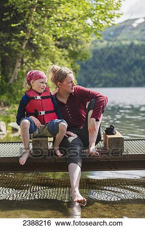 A mother and daughter sits on a dock looking out over Byers Lake, soaking their bare feet in the water, Denali State Park; Alaska, United States of America View Large Photo Image Stock Photograph - A mother and daughter sits on a dock looking out over Byers Lake, soaking their bare feet in the water, Denali State Park; Alaska, United States of America. Fotosearch