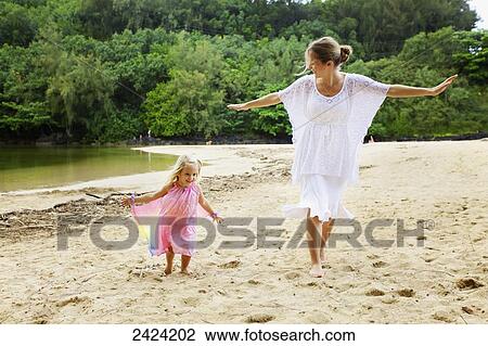 Stock Image - A mother plays on the beach with her young daughter; Kauai, Hawaii, United States of America. Fotosearch