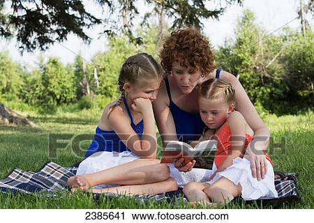 A mother reads a book to her daughters in a park; Stony Plain, Alberta, Canada View Large Photo Image Stock Image - A mother reads a book to her daughters in a park; Stony Plain, Alberta, Canada. Fotosearch