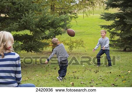 A mother watching her young sons playing football in a park in autumn; Edmonton, Alberta, Canada View Large Photo Image Stock Photograph - A mother watching her young sons playing football in a park in autumn; Edmonton, Alberta, Canada. Fotosearch