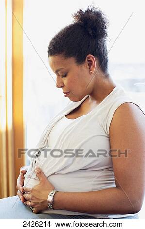 Picture - A pregnant woman with hands on her belly; Toronto, Ontario, Canada. Fotosearch