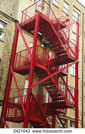 Stock Image - A red metal stairway on the exterior of a residential building, Shoreditch; London, England. Fotosearch