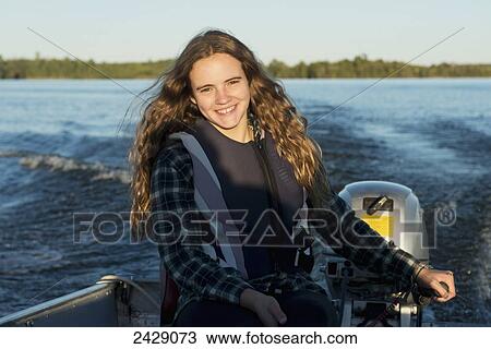 A teenage girl sits by the motor at the back of a motorboat with her face illuminated by sunlight; Ontario, Canada View Large Photo Image Stock Image - A teenage girl sits by the motor at the back of a motorboat with her face illuminated by sunlight; Ontario, Canada. Fotosearch