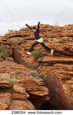 A tourist jumps over a rugged rock formation at Kings Canyon; Northern Territory, Australia View Large Photo Image Picture - A tourist jumps over a rugged rock formation at Kings Canyon; Northern Territory, Australia. Fotosearch