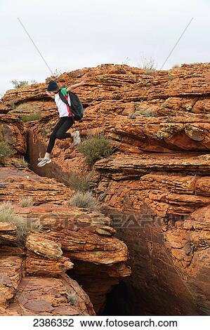 A tourist jumps over a rugged rock formation at Kings Canyon; Northern Territory, Australia View Large Photo Image Stock Image - A tourist jumps over a rugged rock formation at Kings Canyon; Northern Territory, Australia. Fotosearch