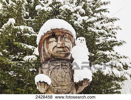Stock Photo - A welcoming totem pole holds a snowman in Cowichan Bay on Vancouver Island; British Columbia, Canada. Fotosearch