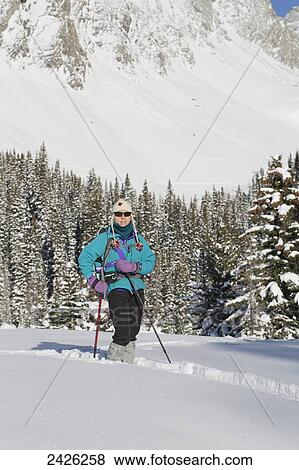 Stock Photo - A woman cross country skiing in deep snow; Banff, Alberta, Canada. Fotosearch