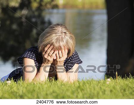 A woman on the grass in a park with her face buried in her hands; Edmonton, Alberta, Canada View Large Photo Image Stock Photograph - A woman on the grass in a park with her face buried in her hands; Edmonton, Alberta, Canada. Fotosearch