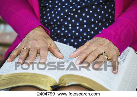 Stock Photo - A woman's hands spread open on her Bible; Edmonton, Alberta, Canada. Fotosearch