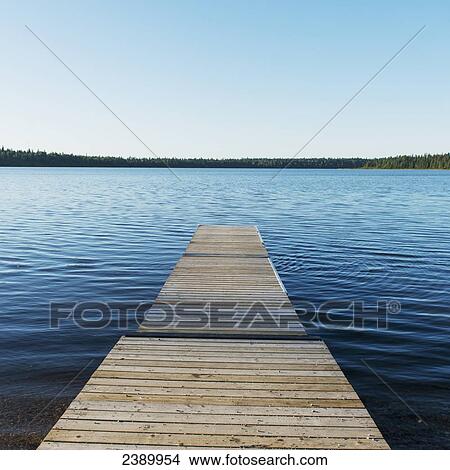 A wooden dock leading out to a lake and blue sky in Riding Mountain National Park; Wasagaming, Manitoba, Canada View Large Photo Image Picture - A wooden dock leading out to a lake and blue sky in Riding Mountain National Park; Wasagaming, Manitoba, Canada. Fotosearch