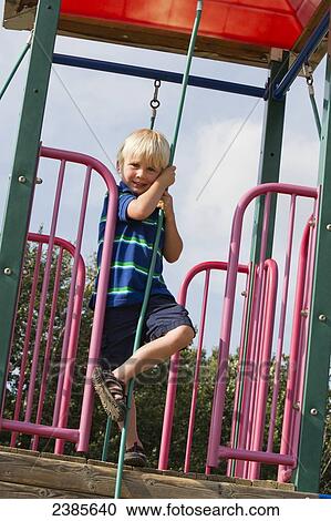 Stock Image - A young boy plays on playground equipment; Stony Plain, Alberta, Canada. Fotosearch