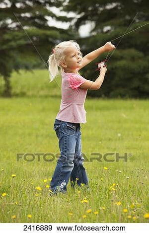 A young girl flying her kite in a field of wildflowers; Thunder Bay, Ontario, Canada View Large Photo Image Stock Photo - A young girl flying her kite in a field of wildflowers; Thunder Bay, Ontario, Canada. Fotosearch