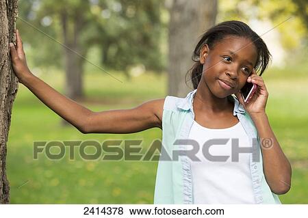 A young girl using a smart phone in a park; Edmonton, Alberta, Canada View Large Photo Image Stock Photo - A young girl using a smart phone in a park; Edmonton, Alberta, Canada. Fotosearch