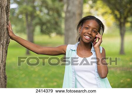 A young girl using a smart phone in a park; Edmonton, Alberta, Canada View Large Photo Image Stock Photo - A young girl using a smart phone in a park; Edmonton, Alberta, Canada. Fotosearch