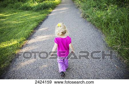 Stock Photo - A young girl walking down a path in a park; St. Albert, Alberta, Canada. Fotosearch
