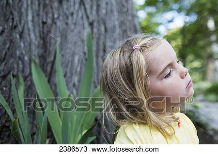 A young girl with a contemplative expression sitting by a tree; Toronto, Ontario, Canada View Large Photo Image Stock Image - A young girl with a contemplative expression sitting by a tree; Toronto, Ontario, Canada. Fotosearch