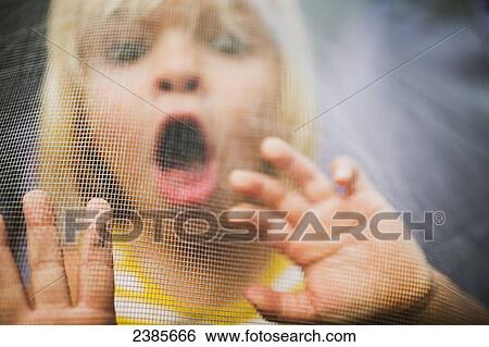 A young girl with a scared expression on her face viewed through a window screen; Peachland, British Columbia, Canada View Large Photo Image Stock Photograph - A young girl with a scared expression on her face viewed through a window screen; Peachland, British Columbia, Canada. Fotosearch