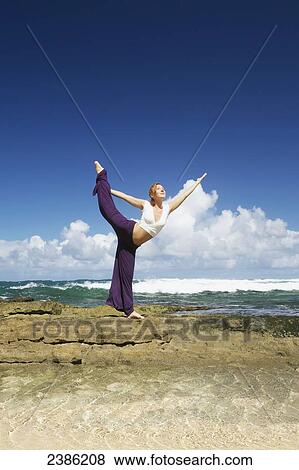 A young woman does a yoga pose on a rock wall at the water's edge; Kauai, Hawaii, United States of America View Large Photo Image Stock Photo - A young woman does a yoga pose on a rock wall at the water's edge; Kauai, Hawaii, United States of America. Fotosearch