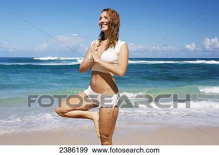 Stock Photo - A young woman does yoga on the beach; Kauai, Hawaii, United States of America. Fotosearch