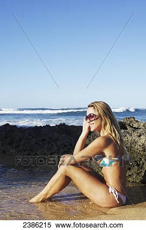 A young woman in a bikini sits in a tide pool on the beach at the water's edge; Hawaii, United States of America View Large Photo Image Stock Photography - A young woman in a bikini sits in a tide pool on the beach at the water's edge; Hawaii, United States of America. Fotosearch