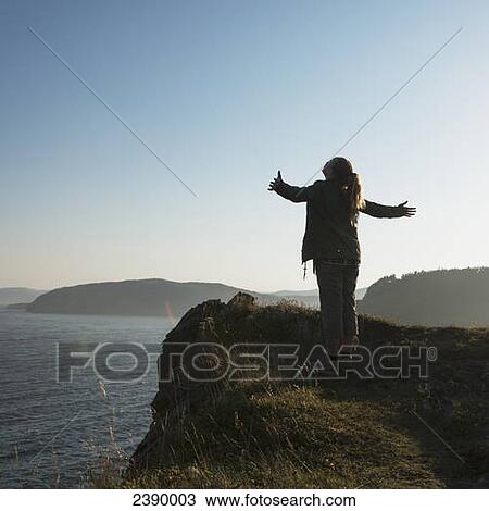 A young woman stands looking up with arms outstretched on a ridge overlooking the Atlantic ocean; Port Rexton, Newfoundland and Labrador, Canada View Large Photo Image Stock Image - A young woman stands looking up with arms outstretched on a ridge overlooking the Atlantic ocean; Port Rexton, Newfoundland and Labrador, Canada. Fotosearch