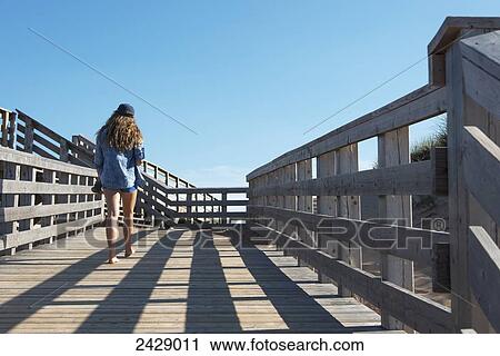 A young woman walking on a wooden boardwalk with blue sky; Prince Edward Island, Canada View Large Photo Image Stock Image - A young woman walking on a wooden boardwalk with blue sky; Prince Edward Island, Canada. Fotosearch