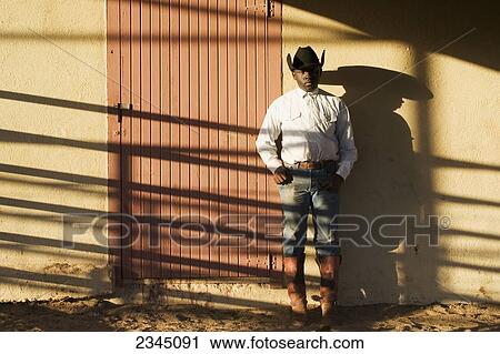 Agriculture - A young black cowboy stands against a bunkhouse wall with late afternoon shadows / Childress, Texas, USA. View Large Photo Image Stock Image - Agriculture - A young black cowboy stands against a bunkhouse wall with late afternoon shadows / Childress, Texas, USA.. Fotosearch