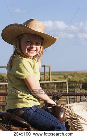 Stock Image - Agriculture - A young cowgirl sitting on a horse smiles at the camera / Childress, Texas, USA.. Fotosearch