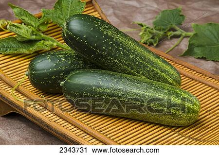 Stock Image - Agriculture - Fresh cucumbers with leaves on a tray.. Fotosearch