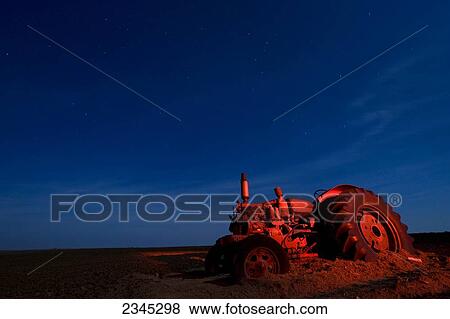 Agriculture - Night view of an old tractor in the dirt lit with a red light and with a starry sky above / Childress, Texas, USA. View Large Photo Image Stock Photo - Agriculture - Night view of an old tractor in the dirt lit with a red light and with a starry sky above / Childress, Texas, USA.. Fotosearch