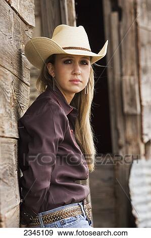 Stock Photo - Agriculture - Portrait of a young cowgirl leaning against an old barn / Childress, Texas, USA.. Fotosearch