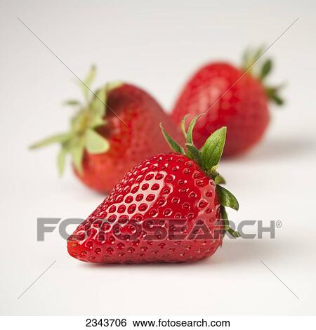 Stock Photograph - Agriculture - Three strawberries on a white surface.. Fotosearch