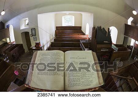 Stock Image - An open bible on a podium in a balcony overlooking wooden pews in a church; Fogo, Scottish Borders, Scotland. Fotosearch
