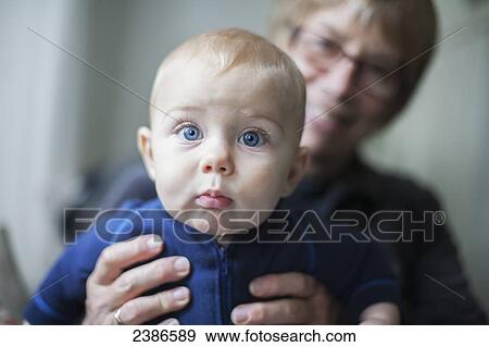 Stock Photo - Baby boy held outstretched by proud grandmother; Toronto, Ontario, Canada. Fotosearch