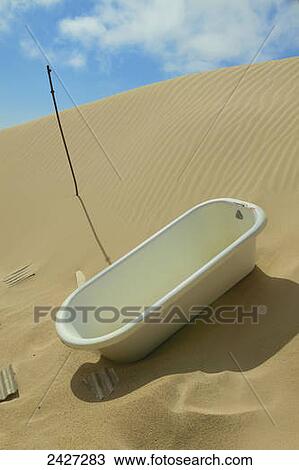 Stock Image - Bathtub from abandoned house overtaken by advancing sand dunes of the Namib Desert; Kolmanskop, Luderitz, Namibia. Fotosearch