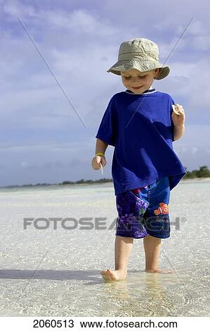Stock Image - Boy Standing In Shallow Water On Beach, Camaguey, Cuba. Fotosearch