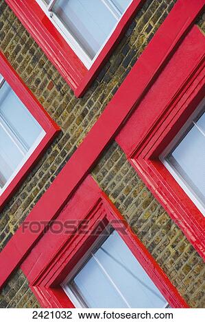 Stock Image - Bright red trim around windows on a brick building; London, England. Fotosearch