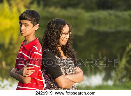 Stock Photo - Brother and sister having a disagreement and ignoring each other; Edmonton, Alberta, Canada. Fotosearch