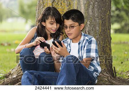 Brother and sister looking at smart phones together in a park; Edmonton, Alberta, Canada View Large Photo Image Stock Image - Brother and sister looking at smart phones together in a park; Edmonton, Alberta, Canada. Fotosearch