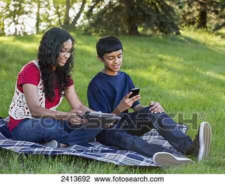 Brother and sister using smart phone and tablet in a park; Edmonton, Alberta, Canada View Large Photo Image Stock Image - Brother and sister using smart phone and tablet in a park; Edmonton, Alberta, Canada. Fotosearch
