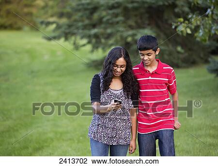 Stock Image - Brother and sister using social media on a smart phone; Edmonton, Alberta, Canada. Fotosearch