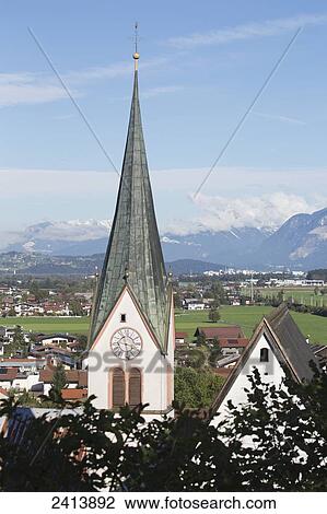 Church steeple in a village with mountain range, blue sky and clouds in the distance; Rattenburg, Austria View Large Photo Image Stock Image - Church steeple in a village with mountain range, blue sky and clouds in the distance; Rattenburg, Austria. Fotosearch