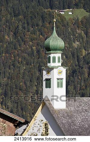 Stock Photograph - Church steeple with tree covered mountain slope in autumn; Aschau, Austria. Fotosearch